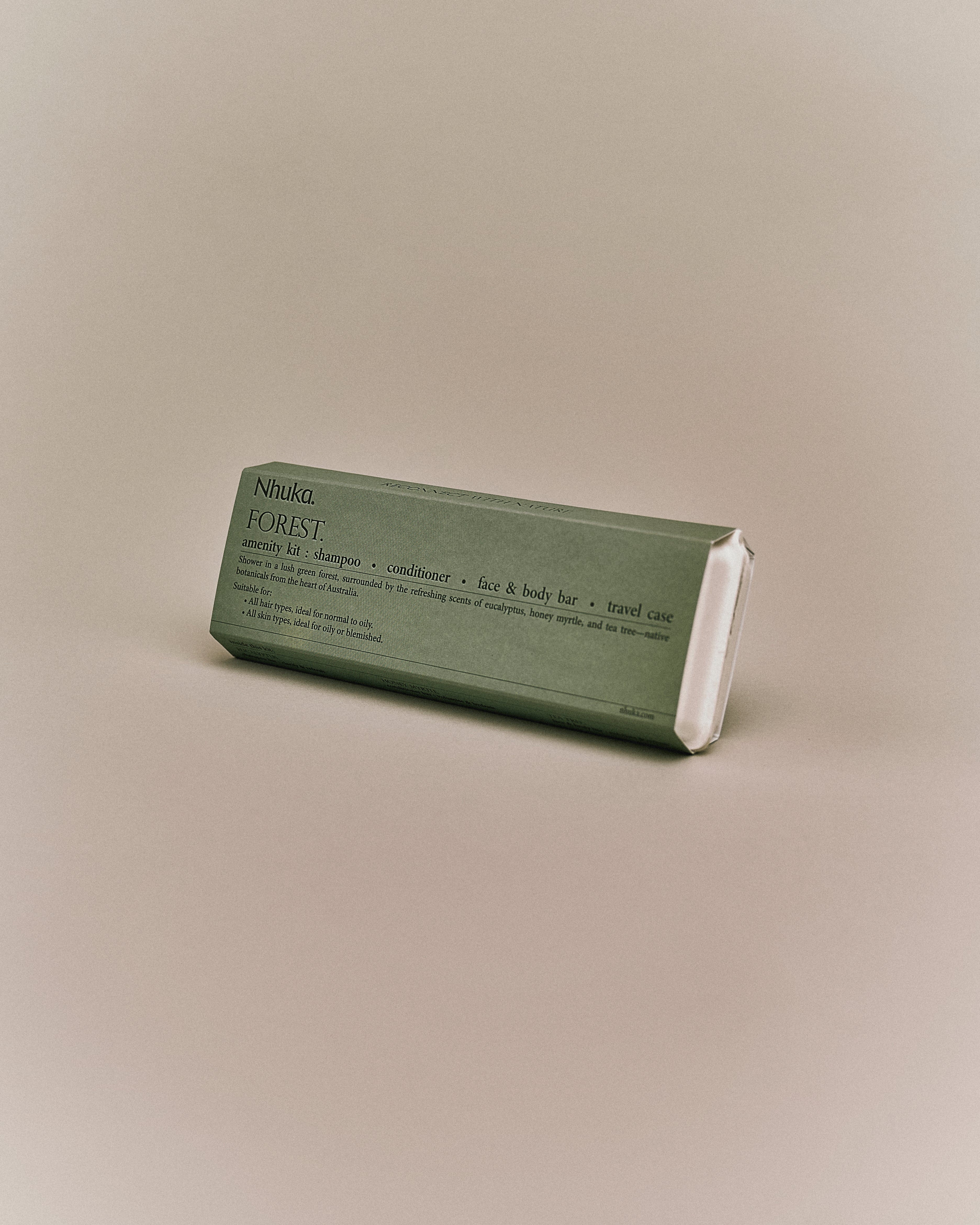 Nhuka Forest Amenity Kit shown at an angle. Includes shampoo, conditioner, face & body bar, and a sugarcane travel case. Refreshing eucalyptus and honey myrtle scent.
