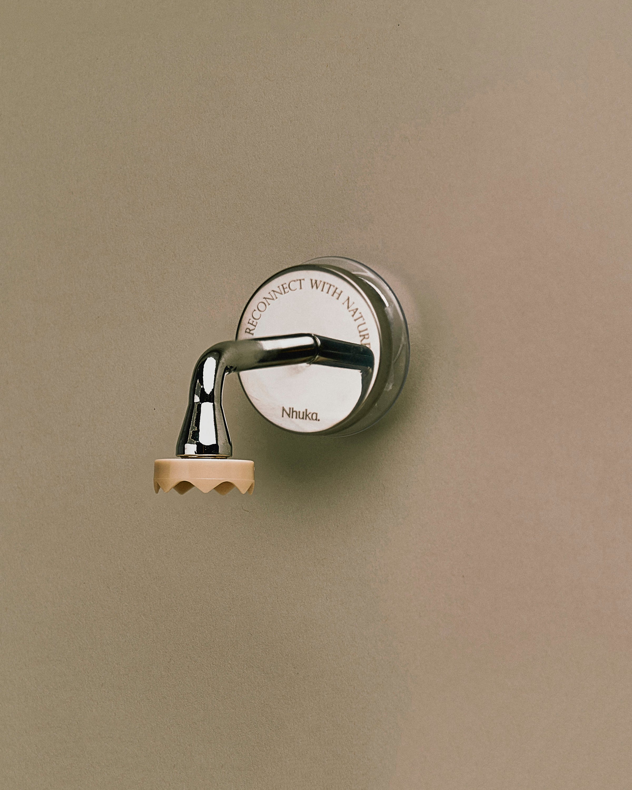Nhuka Branch magnetic bar holder mounted on a smooth surface. Minimalist and functional design with a chrome hook and engraved backplate. Holds bars suspended to keep them dry and ready for use.