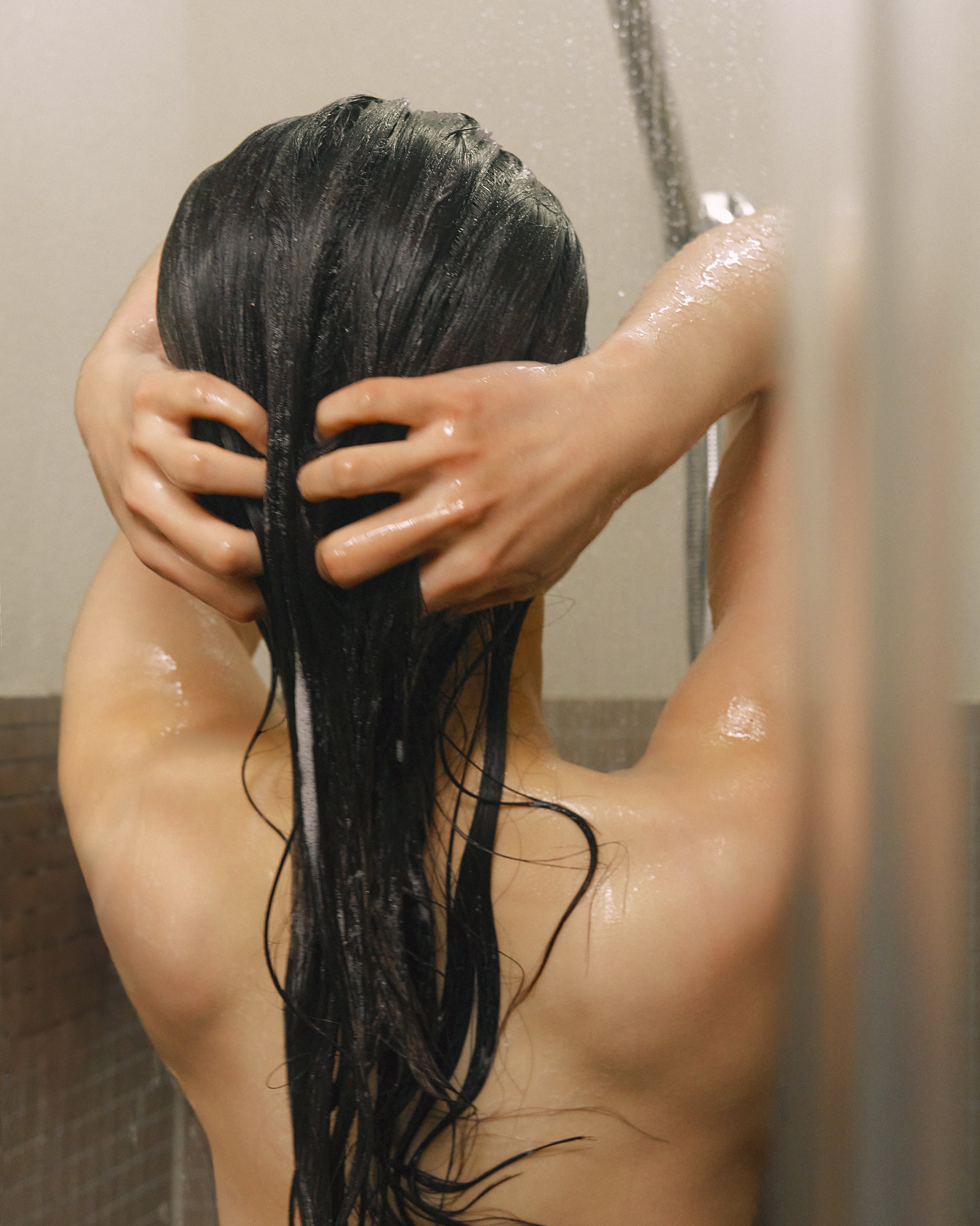 Model rinsing hair after applying Nhuka conditioner bar. Handmade in Australia, silicone-free, pH-balanced, and enriched with organic ingredients to detangle and deeply nourish.