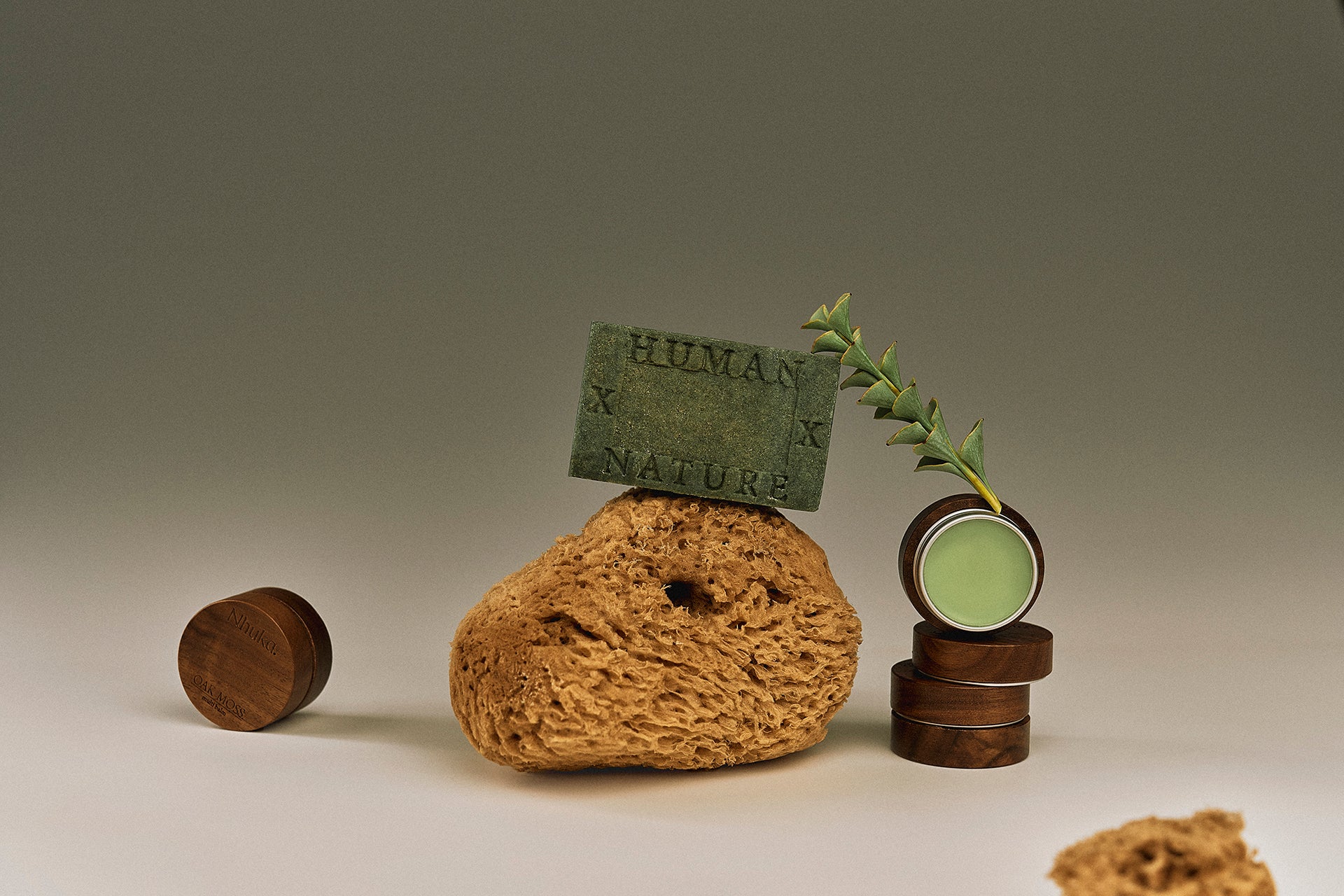 Nhuka One Bar in Oak Moss and Multi Balm styled with loofah and native foliage. Inspired by the grounded stillness of the Australian rainforest. Part of our Rainforest Collection featuring lemon myrtle, tea tree, eucalyptus, and oak moss.