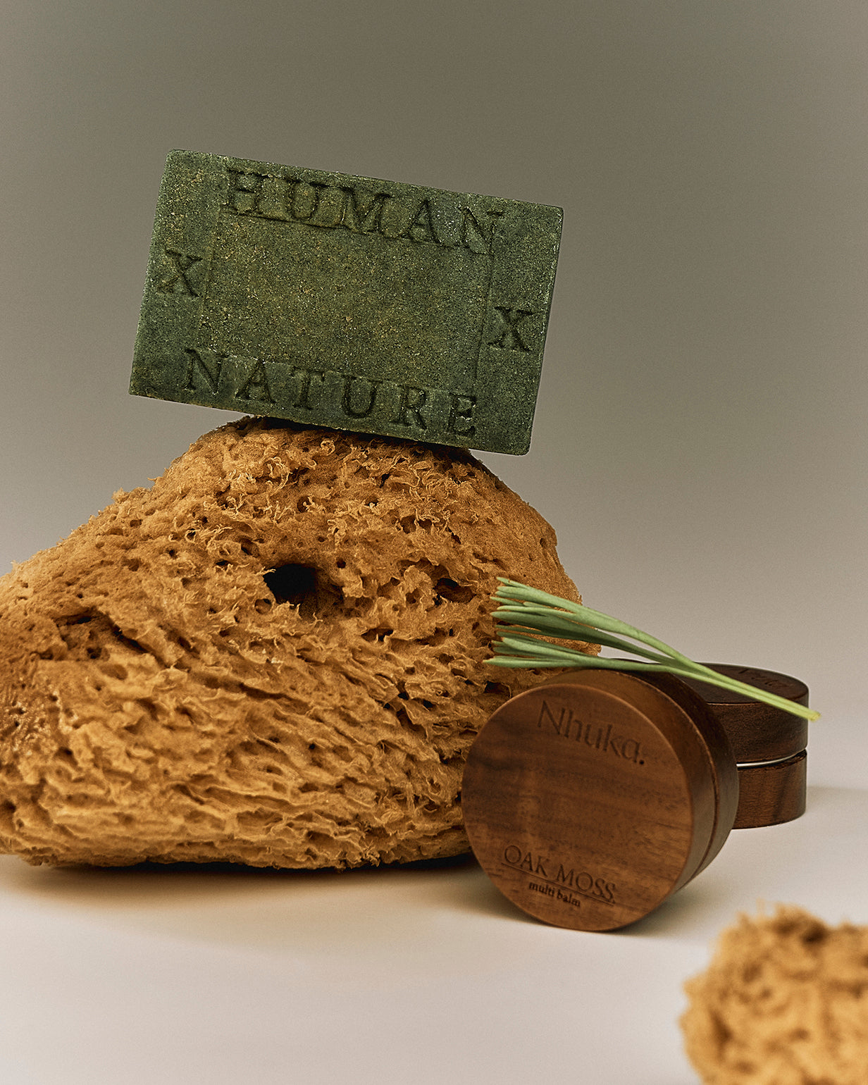 Nhuka One Bar in Oak Moss and Multi Balm styled with loofah and native foliage. Inspired by the grounded stillness of the Australian rainforest. Part of our Rainforest Collection featuring lemon myrtle, tea tree, eucalyptus, and oak moss.