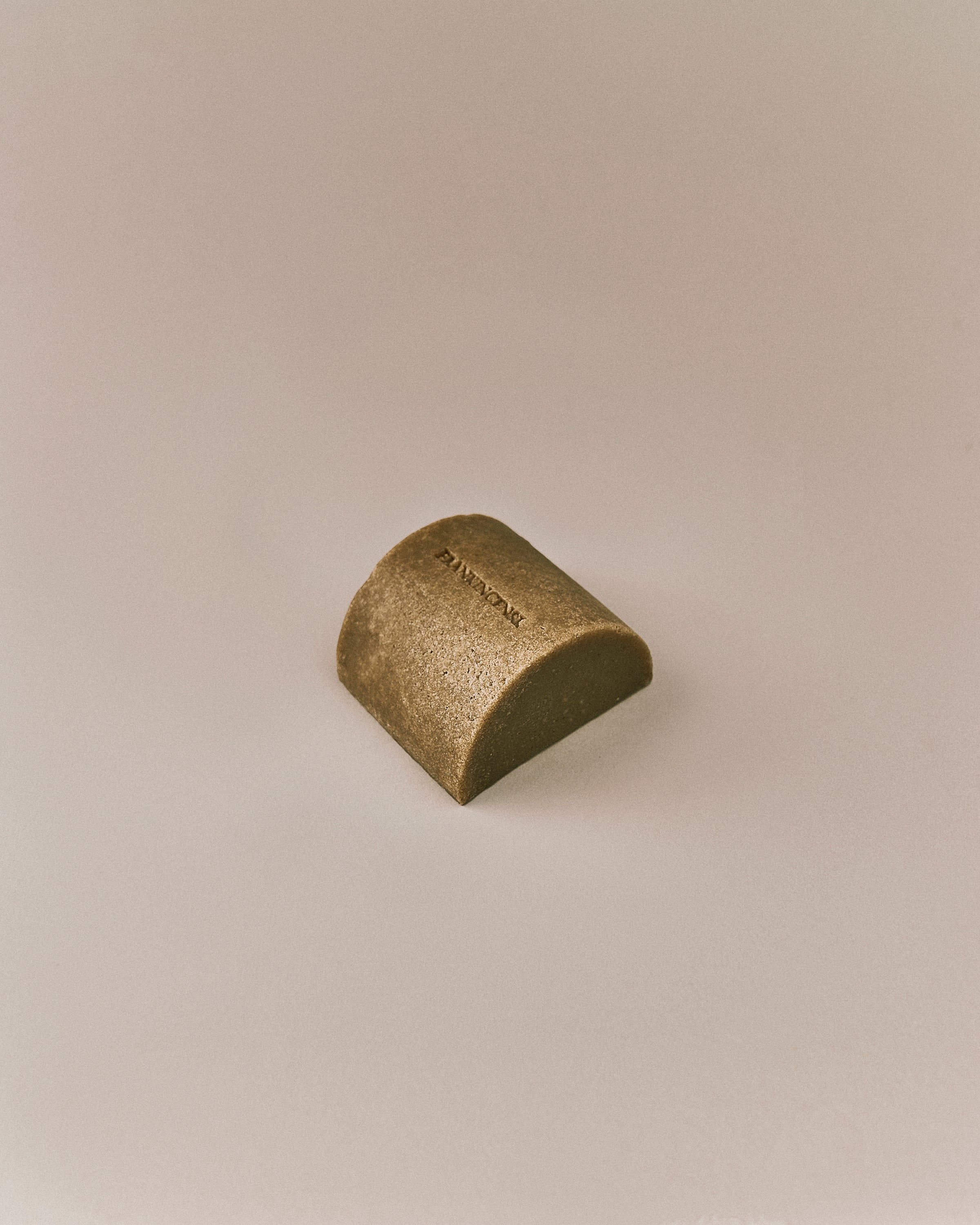 Nhuka organic frankincense soap bar shown at an angle. Organic cold processed soap for face and body with pumice, dead sea mud, and hyaluronic acid.