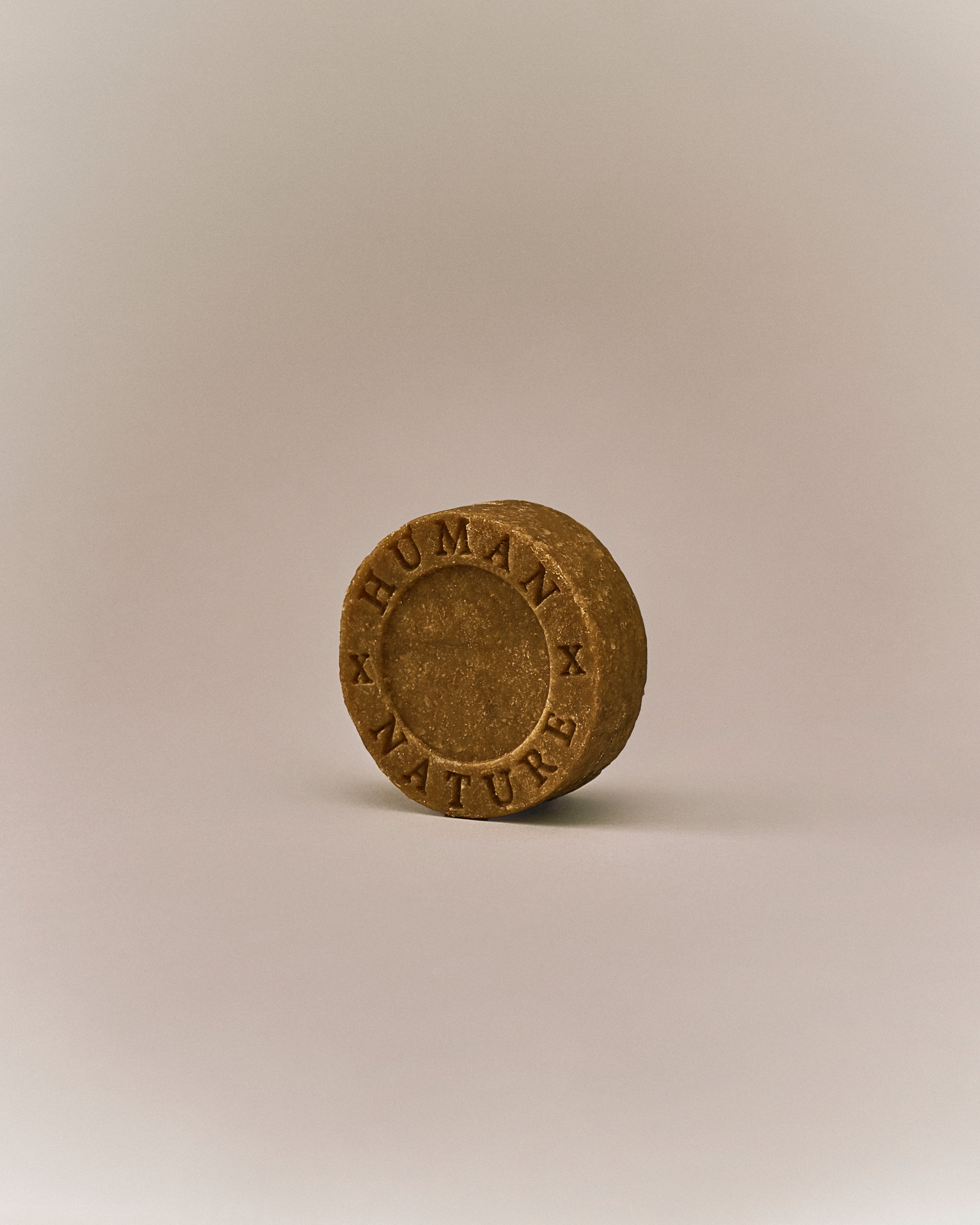 Nhuka organic frankincense shampoo bar shown at an angle with Human x Nature emboss. Handmade in Australia, sulfate-free, silicone-free, pH-balanced for curly, dry, or damaged hair.