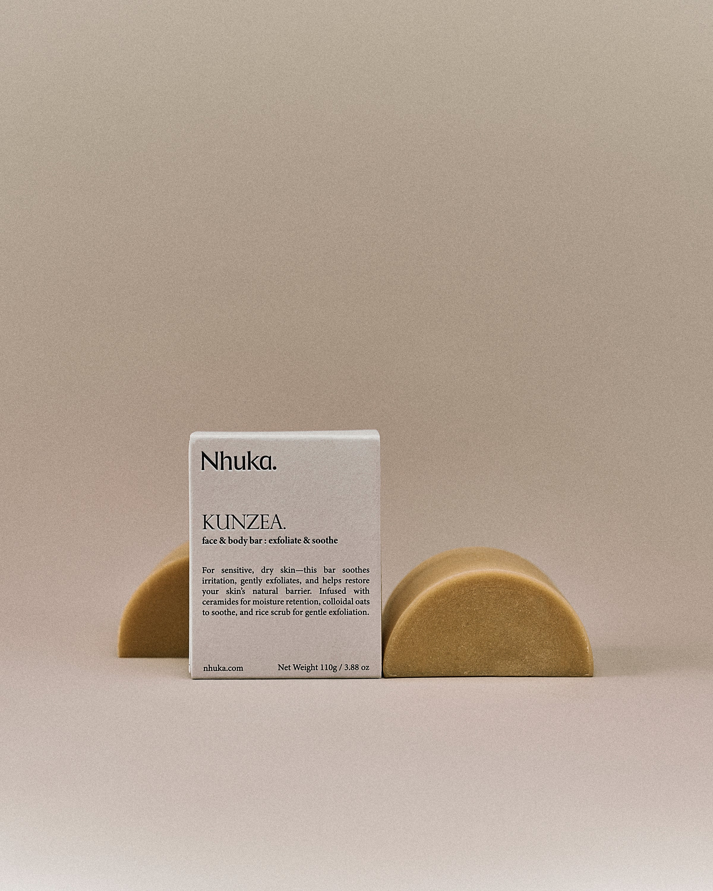 Nhuka organic kunzea face and body soap with FSC-certified paper packaging, flanked by two unwrapped bars. Handmade in Australia for soothing and exfoliating dry, sensitive skin.
