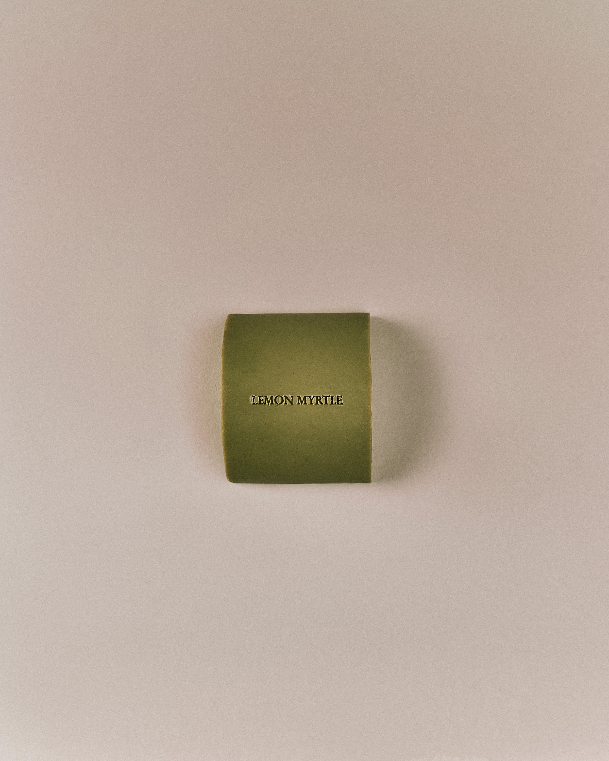 Top view of Nhuka organic lemon myrtle face and body soap bar, embossed with product name. Solid natural cleanser for gentle skin balancing and oil control.