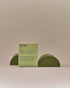 Nhuka organic lemon myrtle face and body soap with FSC-certified paper packaging, flanked by two unwrapped bars. Handmade in Australia for calming and balancing combination skin.