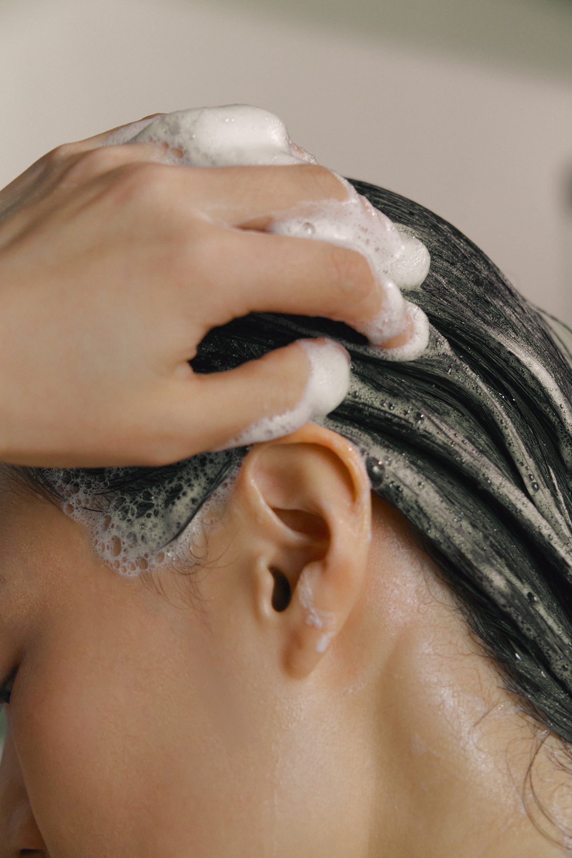 Model applying rich lather from Nhuka organic shampoo bar to hair. Handmade in Australia, pH-balanced, sulfate-free, and silicone-free solid shampoo.