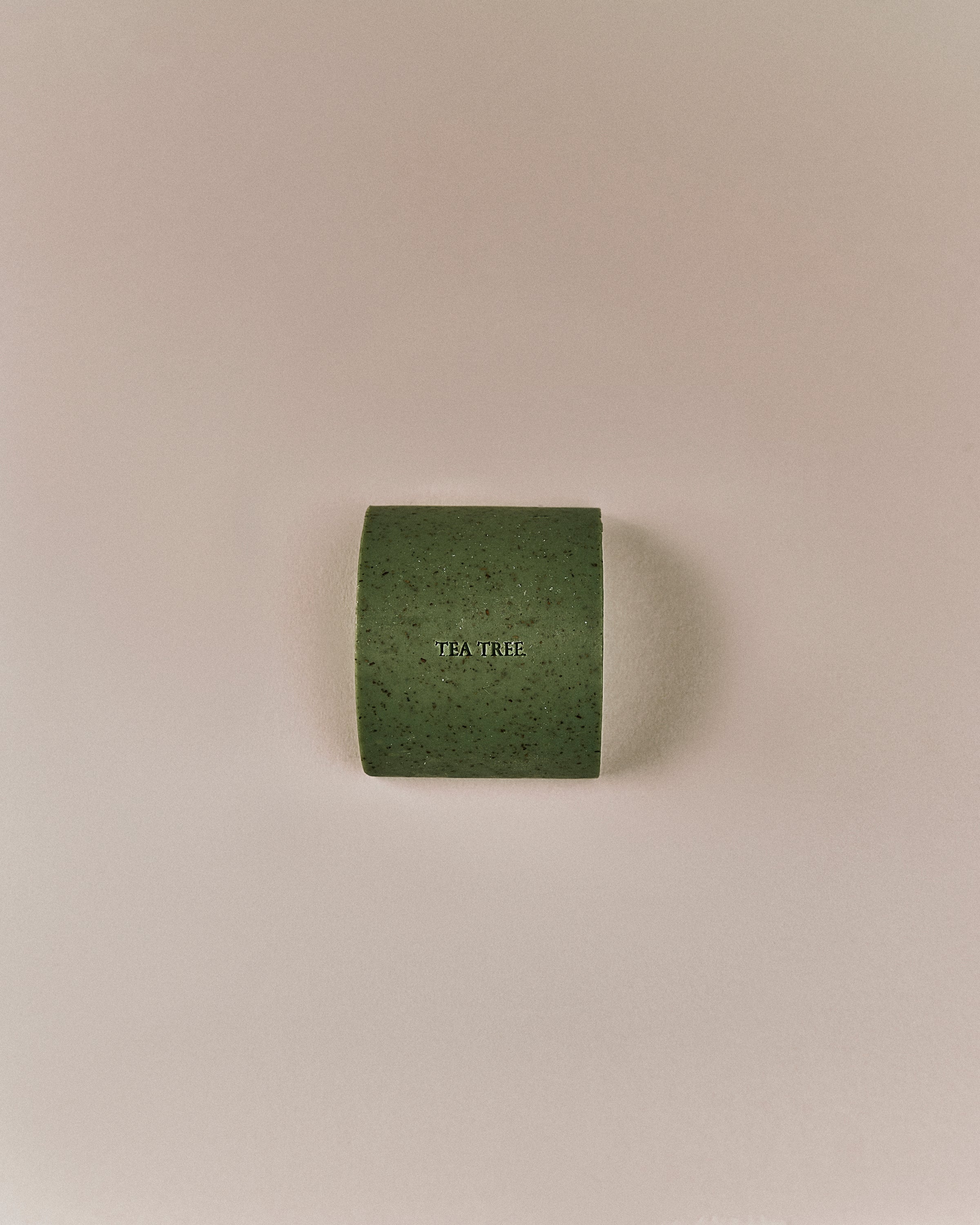 Top view of Nhuka organic tea tree face and body soap bar, embossed with product name. Solid bar for clarifying, cooling, and pore-tightening care.