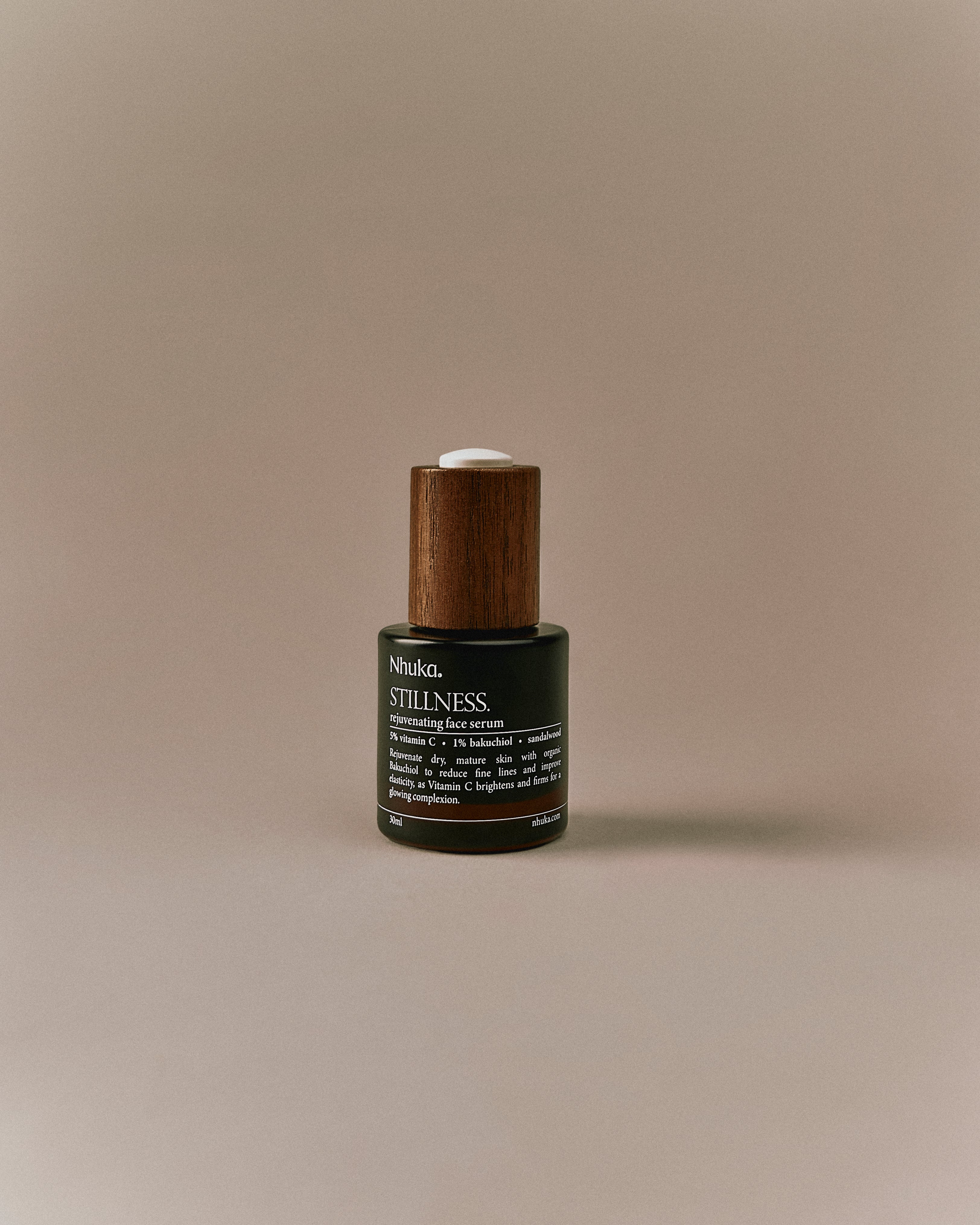 Nhuka Stillness Face Serum bottle with wooden cap. Deep hydration for dry or mature skin. Contains 1% bakuchiol oil and 5% vitamin C to reduce fine lines and support a healthy glow.