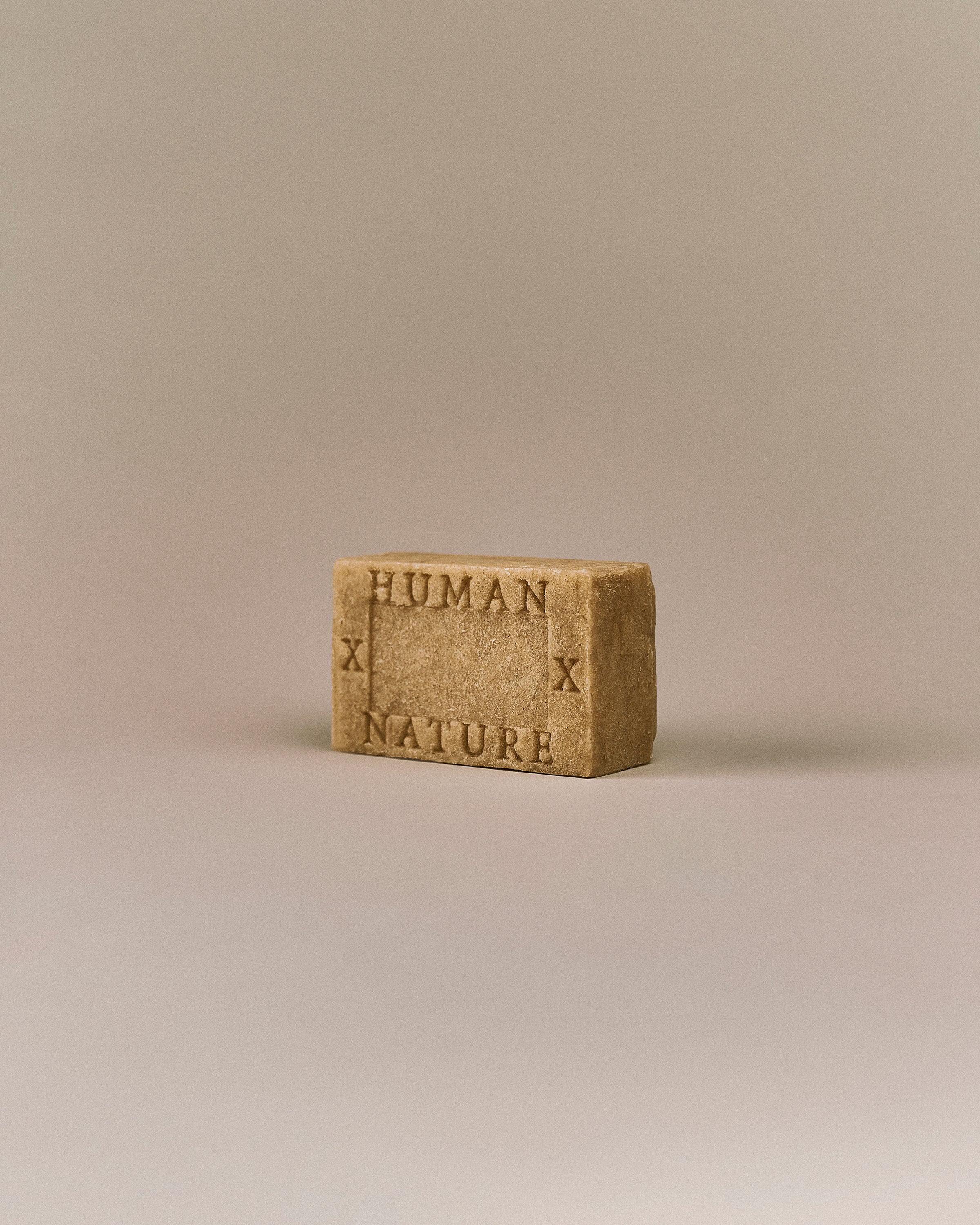 Nhuka White Cypress One Bar shown at an angle with Human x Nature emboss. Handmade in Australia, pH-balanced, sulfate-free, silicone-free, and organic. Smells like a memory of sawdust and pine, gently exfoliating. For hair, face, and body.