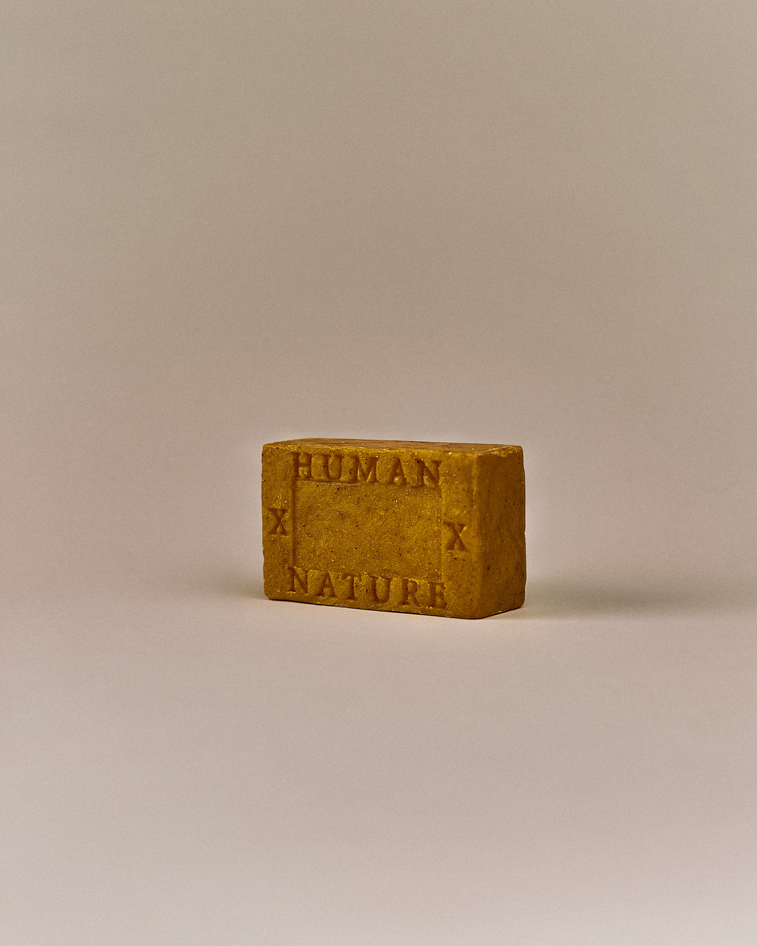 Nhuka Bergamot One Bar shown at an angle with Human x Nature emboss. Handmade in Australia, pH-balanced, sulfate-free, silicone-free, and organic. Bright citrus scent with exfoliating annatto seed. Suitable for hair, face, and body.