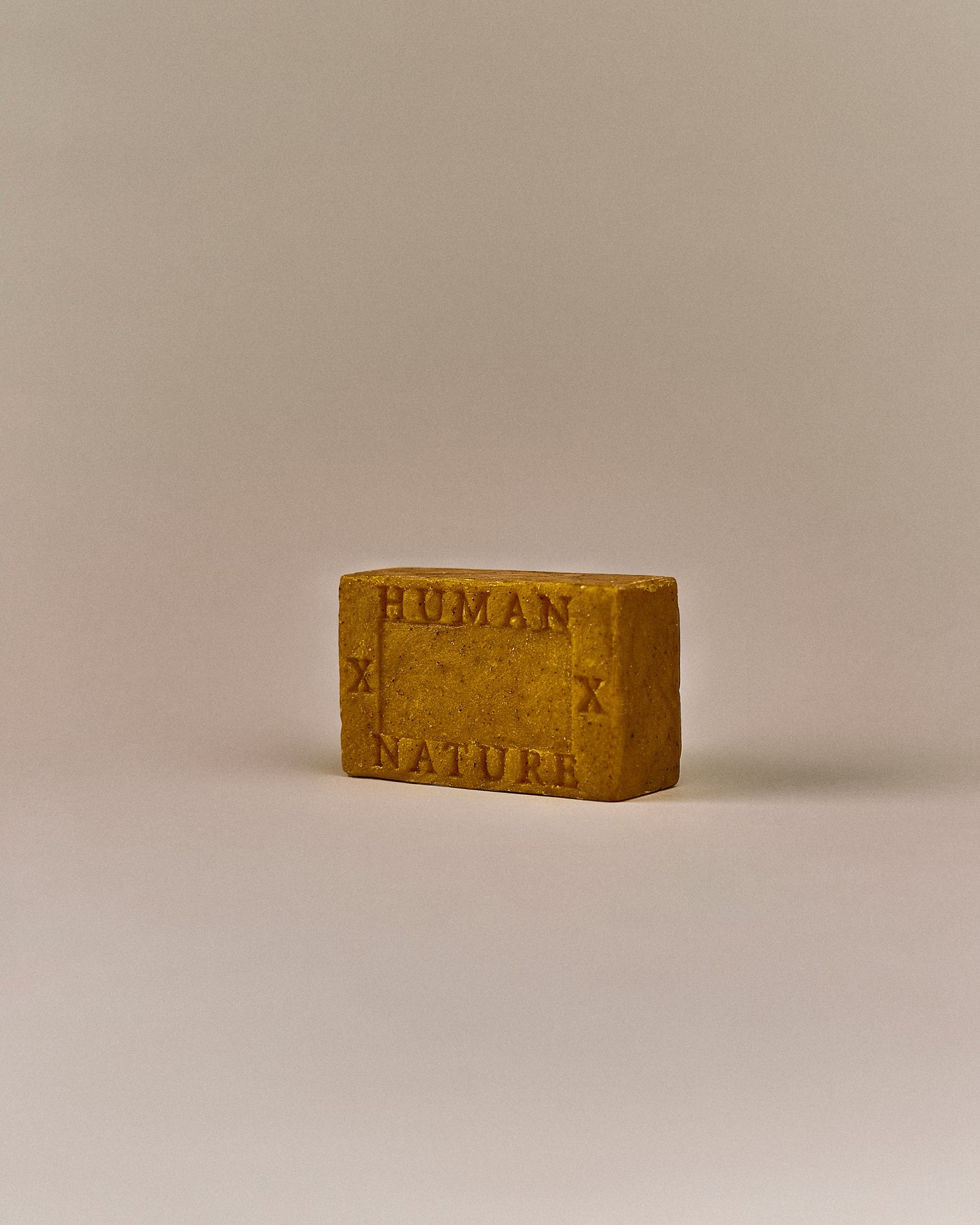 Nhuka Bergamot One Bar shown at an angle with Human x Nature emboss. Handmade in Australia, pH-balanced, sulfate-free, silicone-free, and organic. Bright citrus scent with exfoliating annatto seed. Suitable for hair, face, and body.