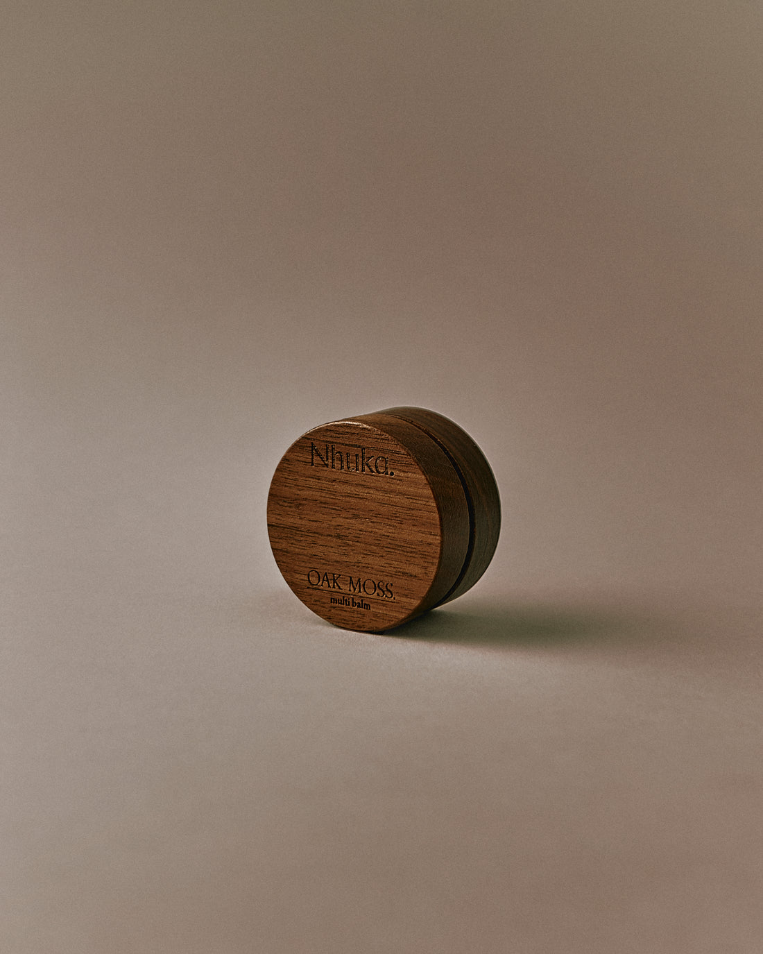 Nhuka Oak Moss Multi Balm shown at an angle. Organic balm to soothe and heal dry or sensitive skin. Features mango butter and rosehip oil with an earthy scent and light, silky texture.