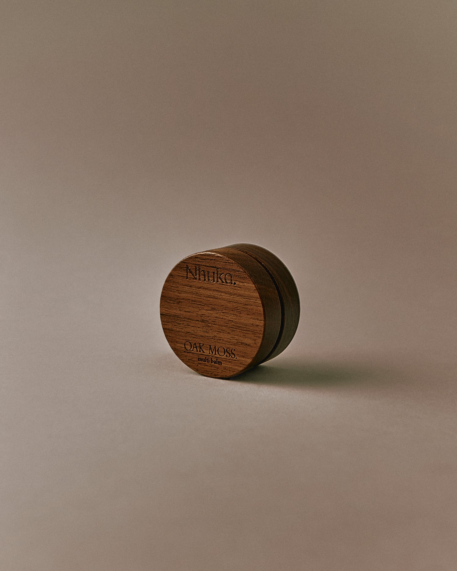 Nhuka Oak Moss Multi Balm shown at an angle. Organic balm to soothe and heal dry or sensitive skin. Features mango butter and rosehip oil with an earthy scent and light, silky texture.