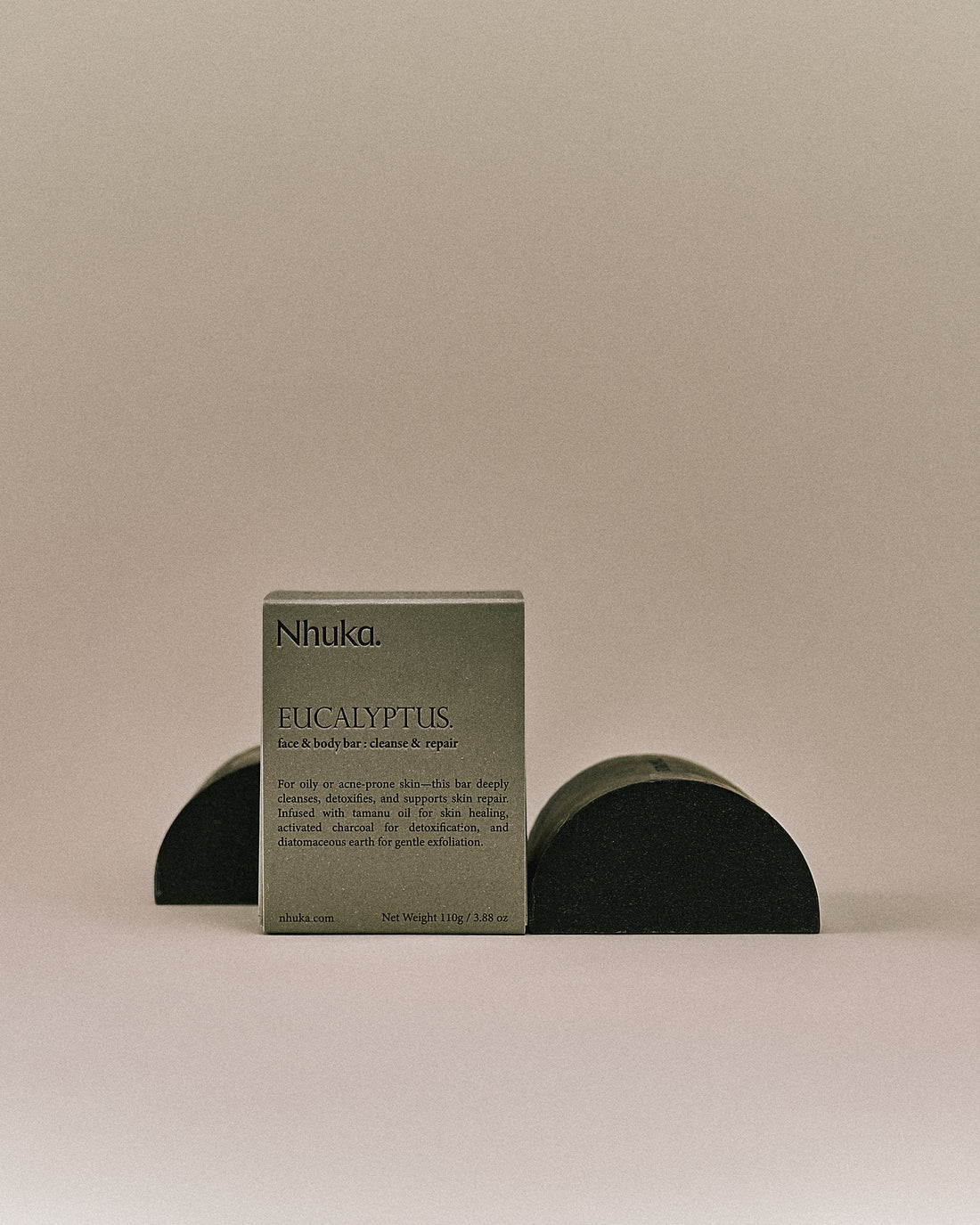 Nhuka organic eucalyptus face and body soap with FSC-certified paper packaging, flanked by two unwrapped bars. Handmade in Australia for cleansing and skin repair. 