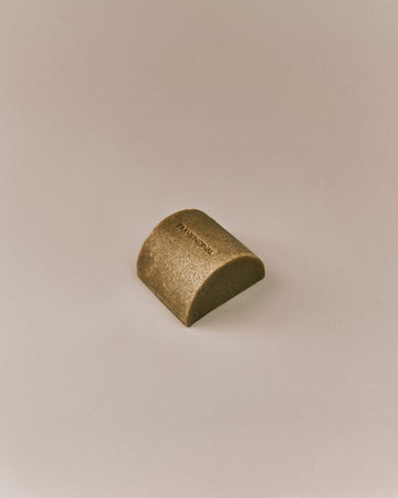 Nhuka organic frankincense soap bar shown at an angle. Organic cold processed soap for face and body with pumice, dead sea mud, and hyaluronic acid.