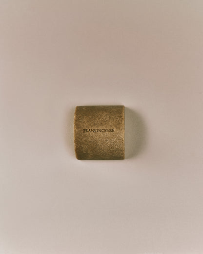 Top-down view of Nhuka organic frankincense face and body soap bar, embossed with product name. Exfoliating soap bar for dry or mature skin.