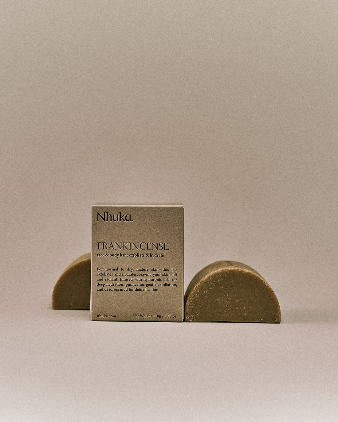 Nhuka organic frankincense face and body soap with FSC-certified paper packaging, flanked by two unwrapped bars. Handmade in Australia for exfoliating and hydrating dry or mature skin.