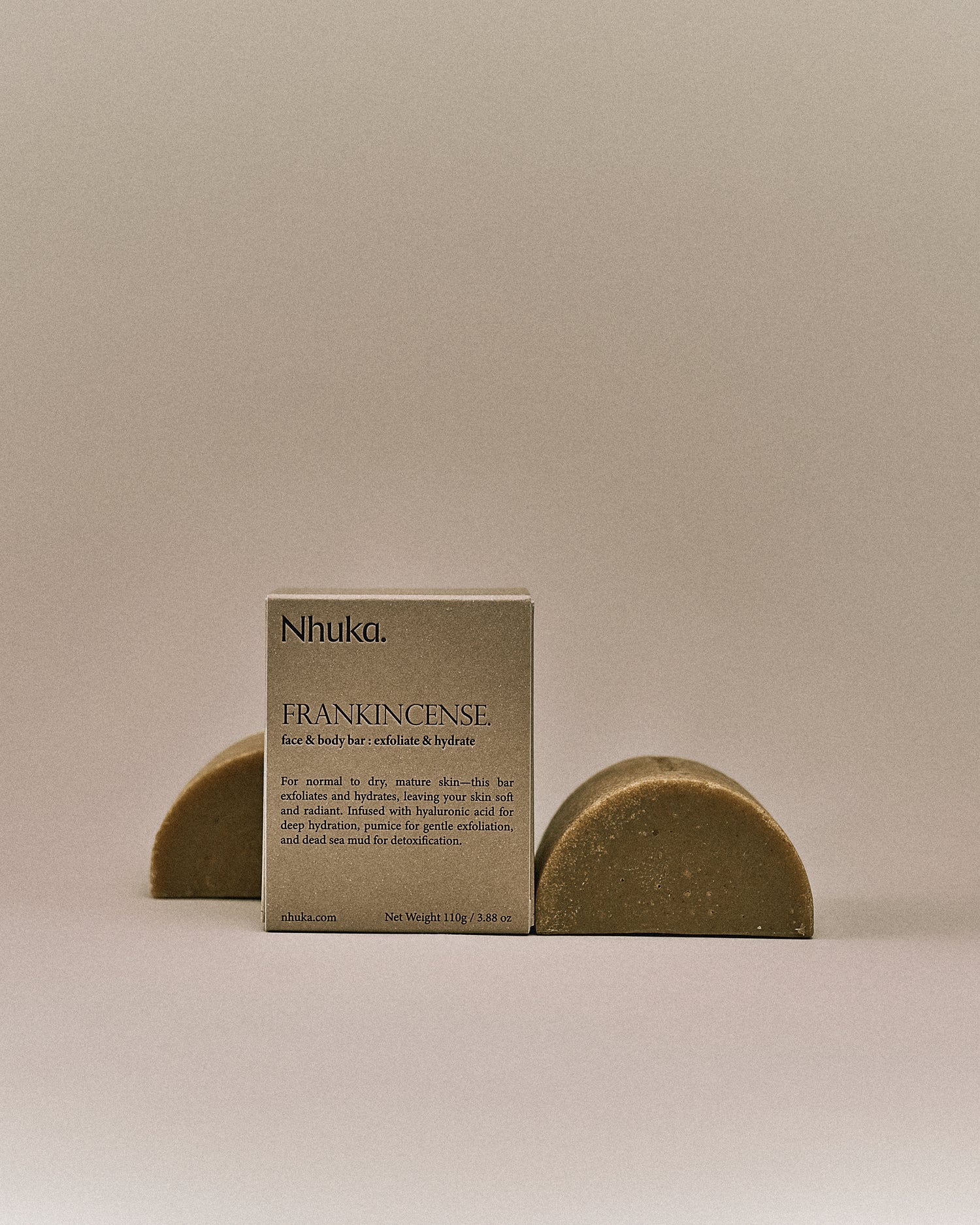 Nhuka organic frankincense face and body soap with FSC-certified paper packaging, flanked by two unwrapped bars. Handmade in Australia for exfoliating and hydrating dry or mature skin.