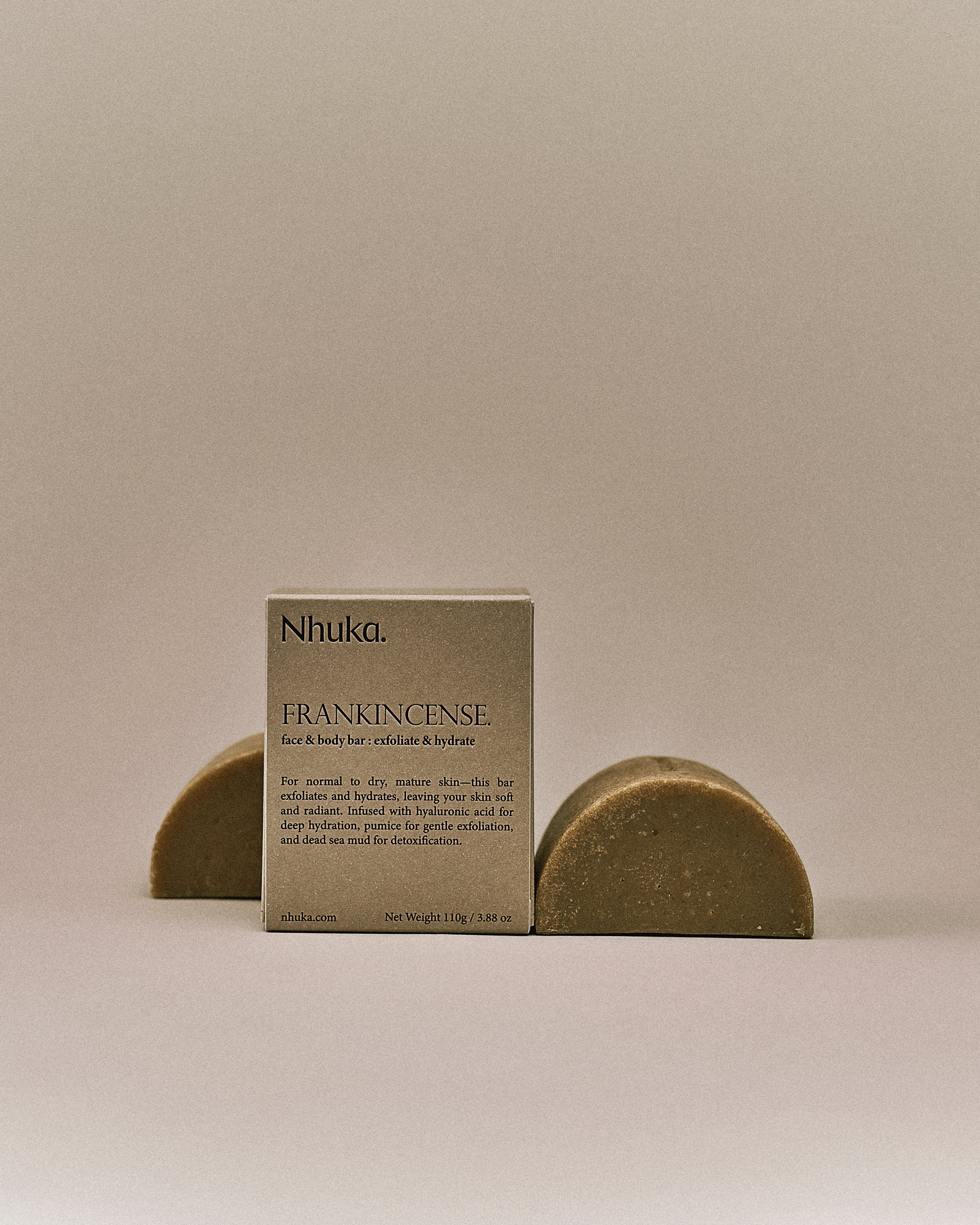 Nhuka organic frankincense face and body soap with FSC-certified paper packaging, flanked by two unwrapped bars. Handmade in Australia for exfoliating and hydrating dry or mature skin.