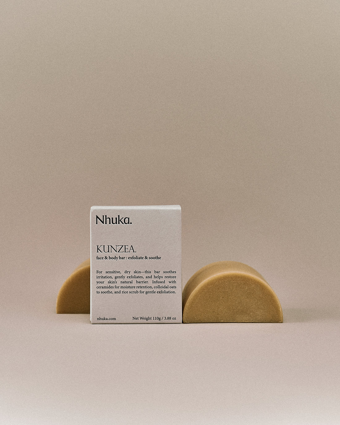 Nhuka organic kunzea face and body soap with FSC-certified paper packaging, flanked by two unwrapped bars. Handmade in Australia for soothing and exfoliating dry, sensitive skin.