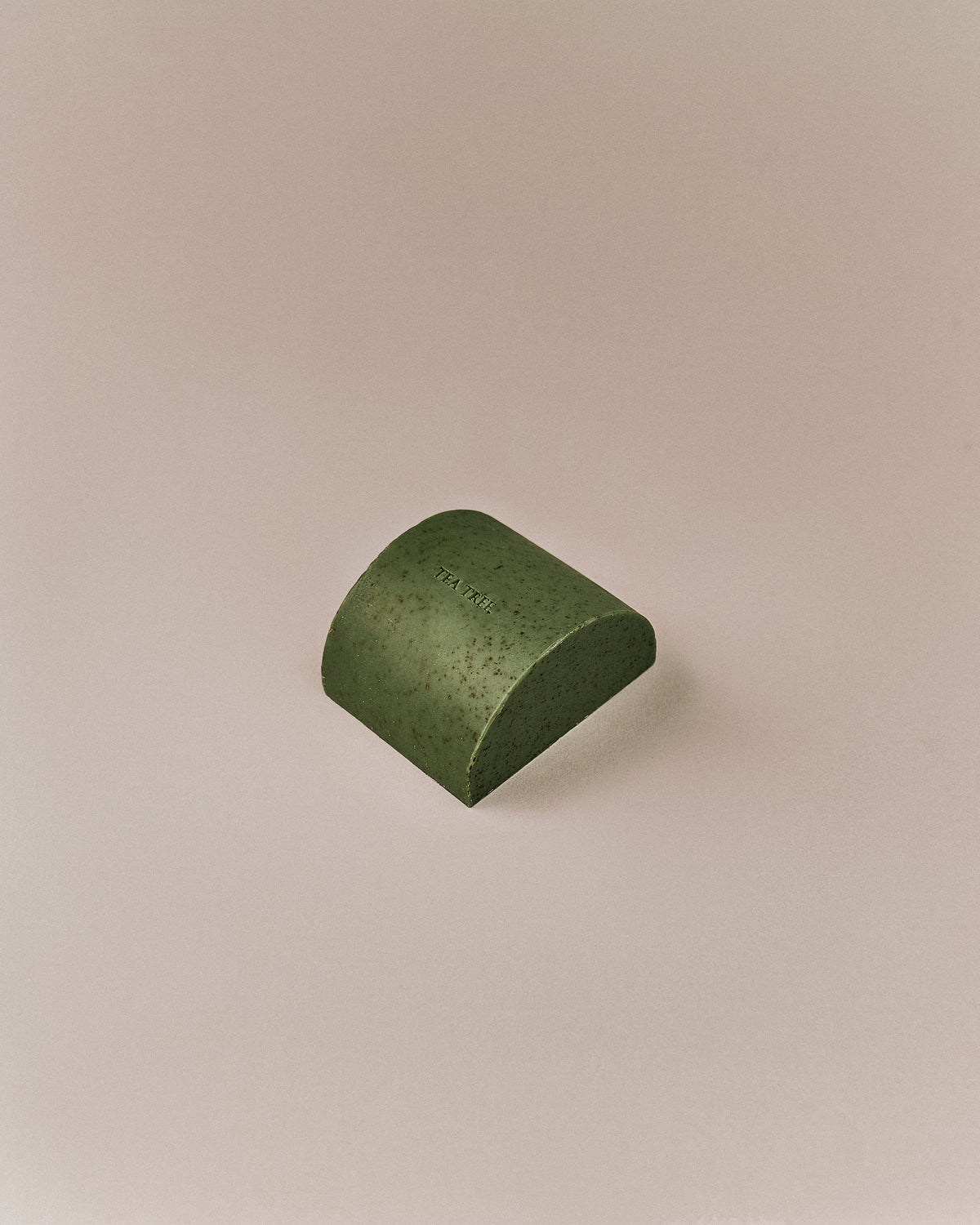 Nhuka organic tea tree soap bar shown at an angle. Solid exfoliating soap with green clay, tea tree leaf, and menthol for blemished skin.