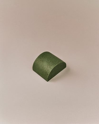 Nhuka organic tea tree soap bar shown at an angle. Solid exfoliating soap with green clay, tea tree leaf, and menthol for blemished skin.