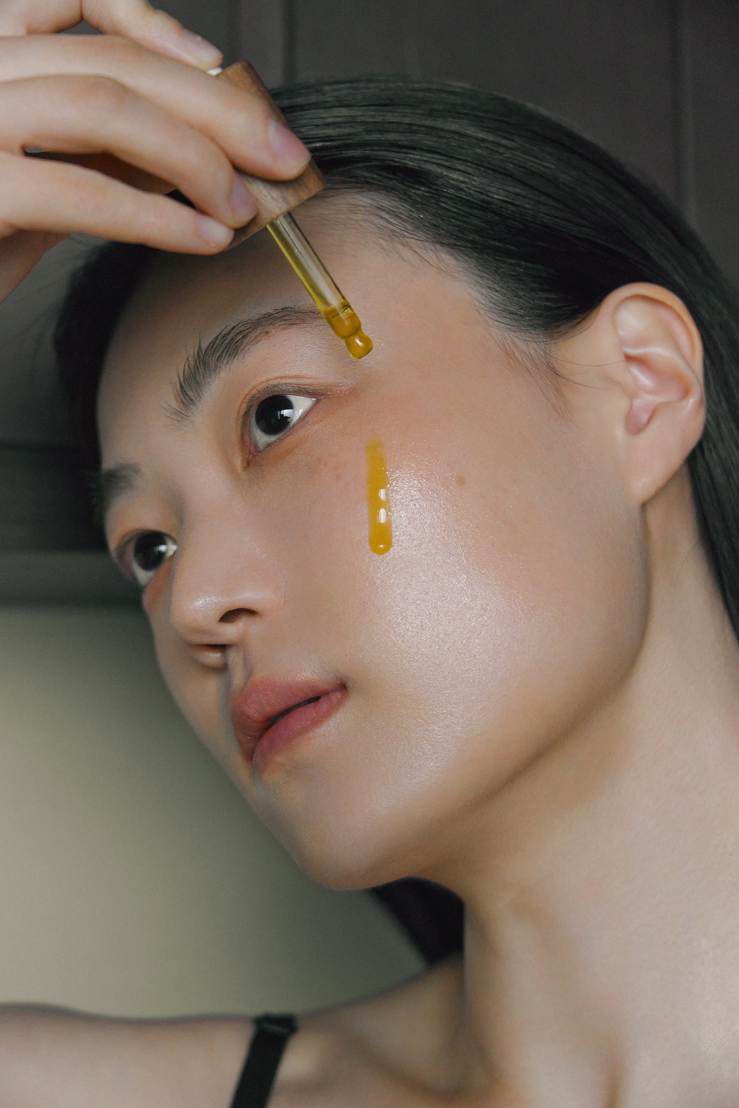 Model applying Nhuka Restoration Face Serum with dropper. A calming and restorative formula for sensitive or combination skin, enriched with ceramides and organic oils.