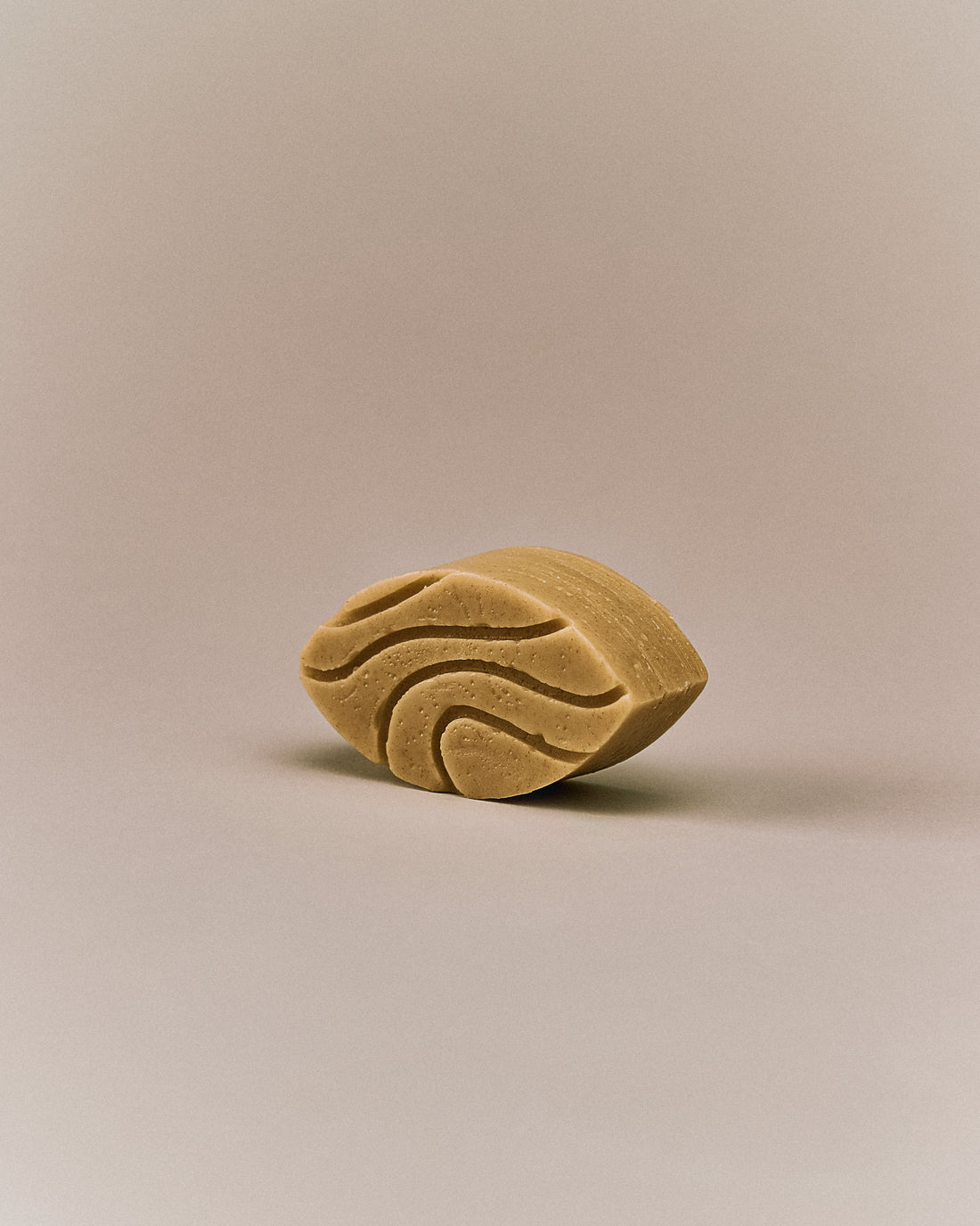Nhuka sandalwood conditioner bar shown at an angle. Organic, pH-balanced, and silicone-free. Formulated to soften, detangle, and reduce frizz for dry or wavy hair.