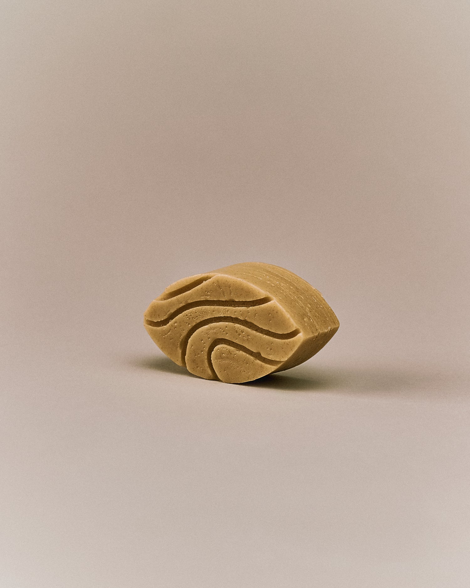 Nhuka sandalwood conditioner bar shown at an angle. Organic, pH-balanced, and silicone-free. Formulated to soften, detangle, and reduce frizz for dry or wavy hair.