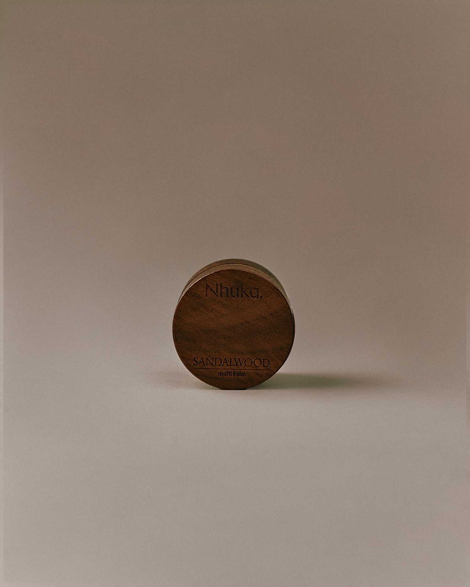 Nhuka Sandalwood Multi Balm shown front on. A velvety-rich balm with organic shea butter, hempseed oil, and beeswax to deeply hydrate and repair dry skin. Earthy, soft scent with subtle herbal notes of sandalwood, sage, and vanilla.