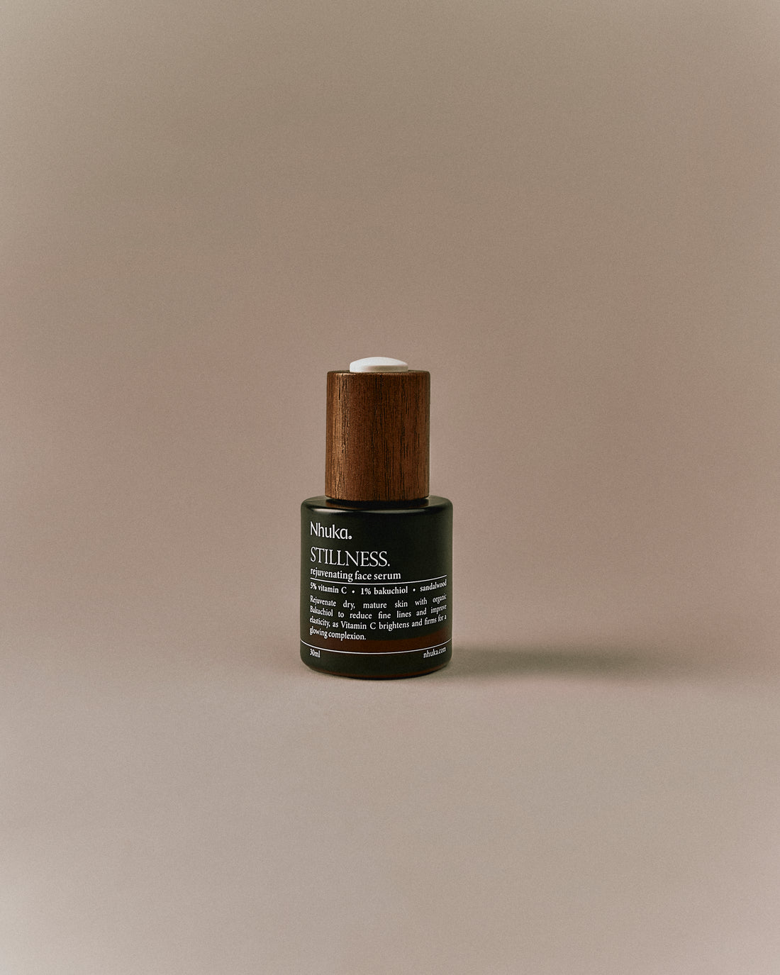Nhuka Stillness Face Serum bottle with wooden cap. Deep hydration for dry or mature skin. Contains 1% bakuchiol oil and 5% vitamin C to reduce fine lines and support a healthy glow.
