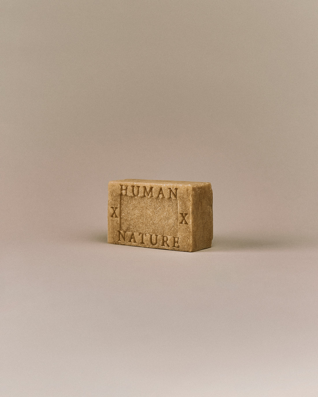 Nhuka White Cypress One Bar shown at an angle with Human x Nature emboss. Handmade in Australia, pH-balanced, sulfate-free, silicone-free, and organic. Smells like a memory of sawdust and pine, gently exfoliating. For hair, face, and body.